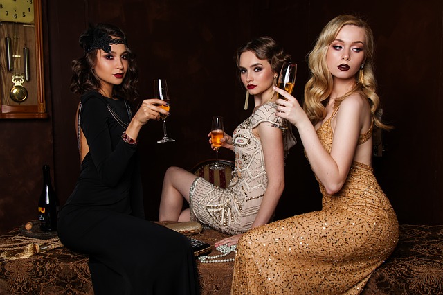 tři ženy v luxusních šatech s vínem v ruce